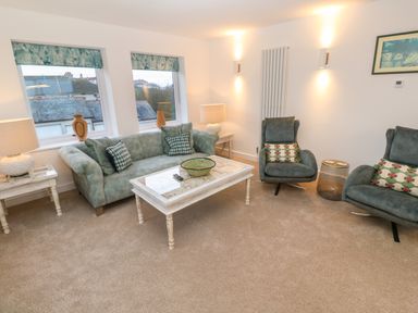 A living room with two armchairs a sofa coffee table side tables and lamps at Fal View in Falmouth