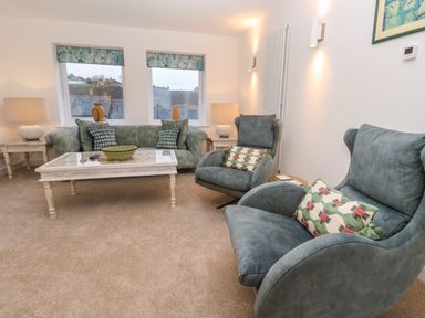 A living room with armchairs sofa coffee table and lamps at Fal View in Falmouth