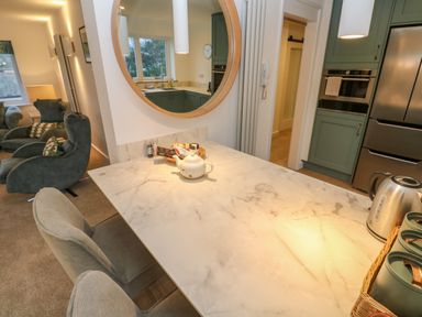 A kitchen with a marble countertop and green cabinets next to a living room with armchairs at Fal View in Falmouth