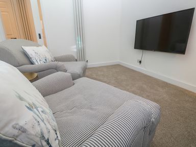 A room with two striped armchairs with cushions and a wall-mounted television at Fal View in Falmouth