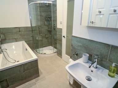 A bathroom with a bathtub shower unit and sink at Fal View in Falmouth