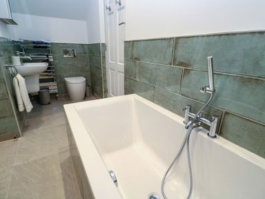 A bathroom with a bathtub sink toilet towel rack and tiled walls at Fal View in Falmouth