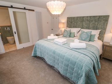 A bedroom with a bed covered with a blue blanket and pillows next to a sliding door leading to a bathroom at Fal View in Falmouth