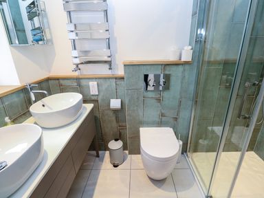 A bathroom with two sinks a toilet a glass shower and a towel rack at Fal View in Falmouth