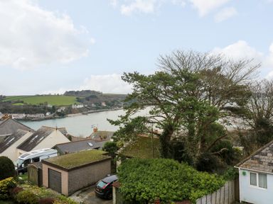A view of houses with a garage trees and a river with hills in the background at Fal View in Falmouth