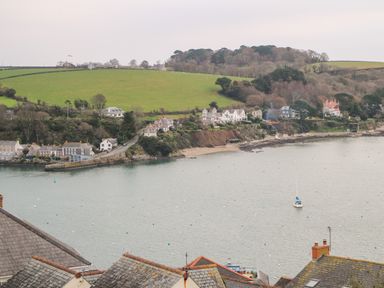 A coastal scene with houses on a hillside and a sailboat on the water at Fal View in Falmouth