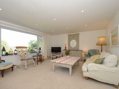 A living room with large window rocking chair and sofa with cushions at Trestar in Polzeath