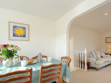 A dining table with cups and a vase of flowers next to a living area with a sofa at Trestar in Polzeath