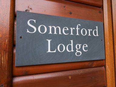 A name sign on wooden paneling that reads Somerford Lodge