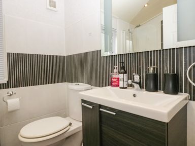A bathroom with a toilet a sink with soap dispensers and a mirror above at Somerford Lodge Langdale 7 White Cross Bay near Windermere