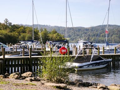 A marina with boats docked at wooden piers and trees in the background at Somerford Lodge Langdale 7 White Cross Bay near Windermere