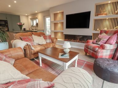 A living room with a sofa, armchair, coffee table, and television at Little Willesleigh in Goodleigh near Barnstaple