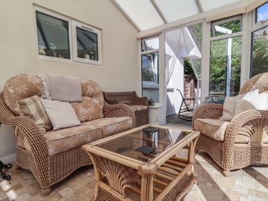 A conservatory with wicker furniture and a glass table at Little Willesleigh in Goodleigh near Barnstaple