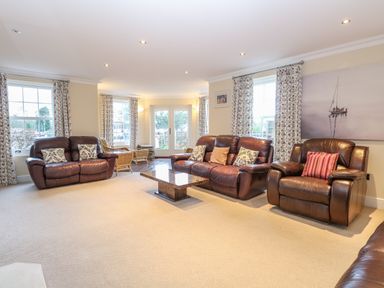 A living room with brown leather sofas and armchairs and a coffee table at The Little House in Horning