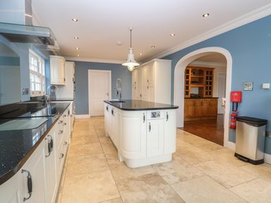 A kitchen with white cabinets black countertops and a central island with a sink at The Little House in Horning