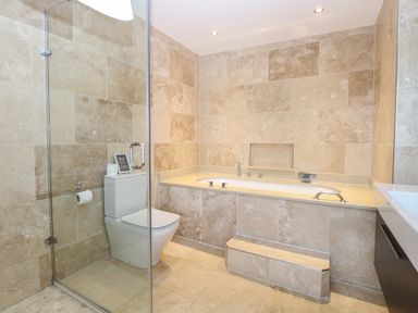 A bathroom with a bathtub toilet and glass shower door at The Little House in Horning