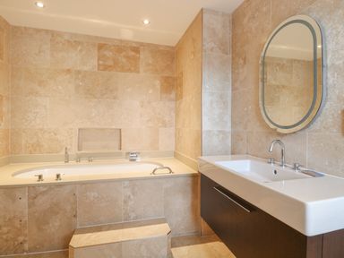 A bathroom with a bathtub with step and a sink with mirror at The Little House in Horning