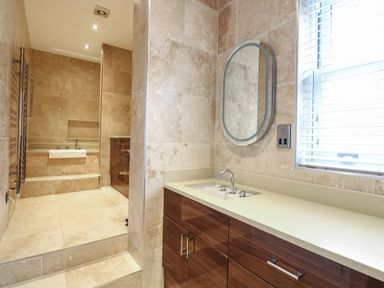 A bathroom with a sink and mirror and a bathtub partially visible behind a wall at The Little House in Horning