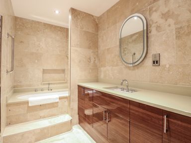 A bathroom with a bathtub and a vanity with a sink and mirror at The Little House in Horning