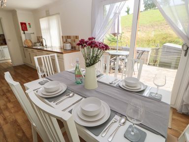 A dining table set with white plates bowls cutlery and wine glasses with a vase of flowers in a kitchen at Butterfly Lodge in Tunstall near Catterick North Yorkshire