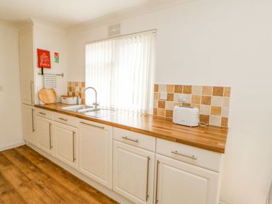 A kitchen with white cabinets wooden countertop a sink toaster and tiled backsplash at Butterfly Lodge in Tunstall near Catterick North Yorkshire