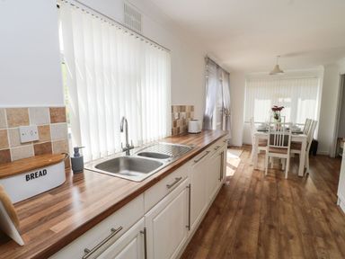 A kitchen with a sink and wooden countertop next to a dining area with a table and chairs at Butterfly Lodge in Tunstall near Catterick North Yorkshire