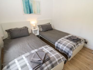 A bedroom with two single beds with grey bedding and folded towels on each bed at Butterfly Lodge in Tunstall near Catterick North Yorkshire