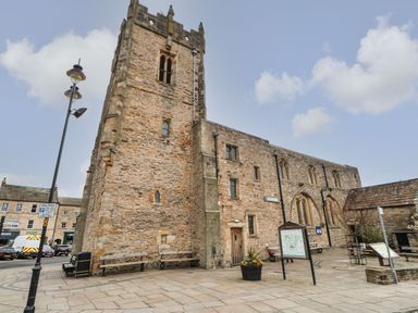 An old stone building with a tower labeled museum in a paved town square with benches and signboards at Butterfly Lodge in Tunstall near Catterick North Yorkshire
