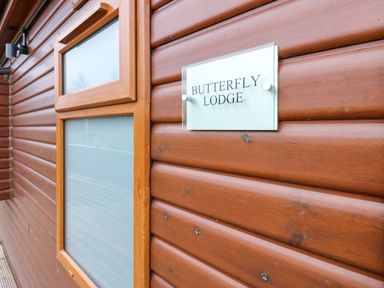 A wooden exterior wall with two frosted windows and a sign reading Butterfly Lodge at Butterfly Lodge in Tunstall near Catterick North Yorkshire