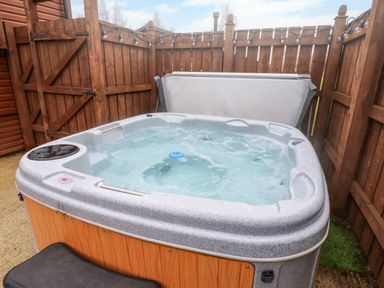 An outdoor hot tub with water inside surrounded by wooden fencing at Butterfly Lodge in Tunstall near Catterick North Yorkshire