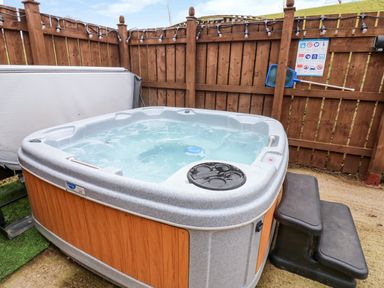 An outdoor hot tub with steps next to a wooden fence at Butterfly Lodge in Tunstall near Catterick North Yorkshire
