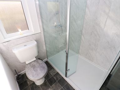 A bathroom with a toilet and a glass-enclosed shower at Butterfly Lodge in Tunstall near Catterick North Yorkshire