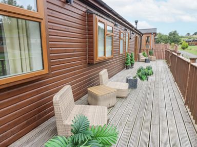A deck area with chairs and plants at Butterfly Lodge Tunstall near Catterick, North Yorkshire