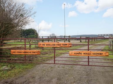 A gate with signs leading to The Wireless Free Farm in Y Trallwng