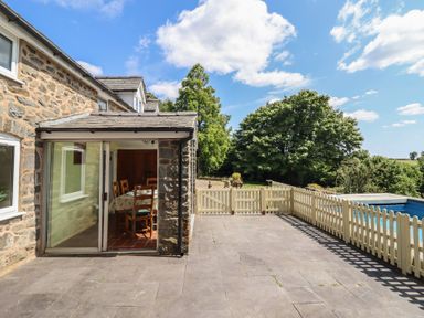 An outdoor area with a stone wall and dining table at Bryn Y Garreg Cottage - The Wireless Free Farm in Llangadfan near Llanwddyn
