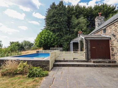 An outdoor area with a swimming pool and a stone house at Bryn Y Garreg Cottage - The Wireless Free Farm in Llangadfan near Llanwddyn