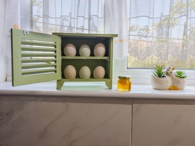 A kitchen window with a wooden cabinet holding eggs and a honey jar at Bryn Y Garreg Cottage - The Wireless Free Farm Llangadfan near Llanwddyn