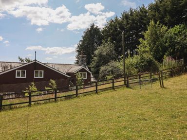 A building with a fence and trees in a field at Bryn Y Garreg Cottage - The Wireless Free Farm Llangadfan near Llanwddyn
