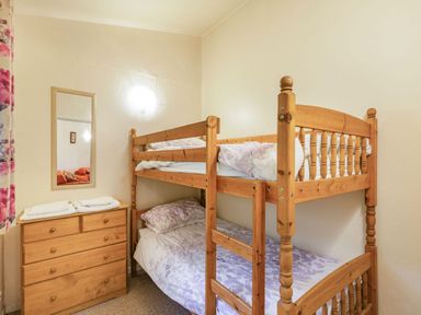 A bedroom with a wooden bunk bed and a wooden chest of drawers with towels on top at The Log Cabin in Sheldon Blackdown Hills
