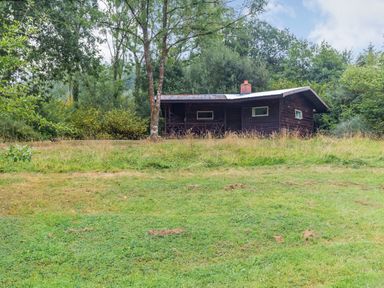 A wooden cabin surrounded by trees and grass at The Log Cabin in Sheldon Blackdown Hills