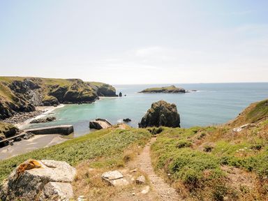 A coastal path leading down to a small harbor with sea and rocky cliffs at Savoy View in Mullion