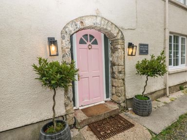 A pink door with stone arch and two plants in pots at Norchard Farm House Redberth near St Florence