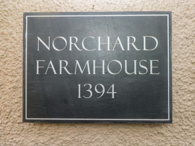 A sign on a textured wall reading Norchard Farmhouse 1394