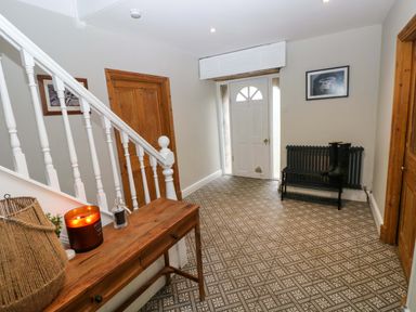 An entrance hallway with a white door a wooden table by white stairs and wooden doors at Norchard Farm House Redberth near St Florence