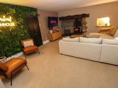A living room with a fireplace a wall-mounted tv and sofas at Norchard Farm House in Redberth near St Florence