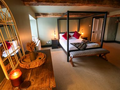A bedroom with a four poster bed bedside tables bench and a wooden dresser with a candle at Norchard Farm House Redberth near St Florence