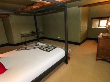 A bedroom with a four-poster bed chest of drawers and a small window at Norchard Farm House in Redberth near St Florence