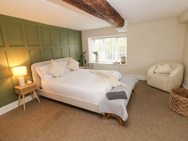 A bedroom with a bed a side table with lamp a window an armchair and a wicker basket at Norchard Farm House in Redberth near St Florence