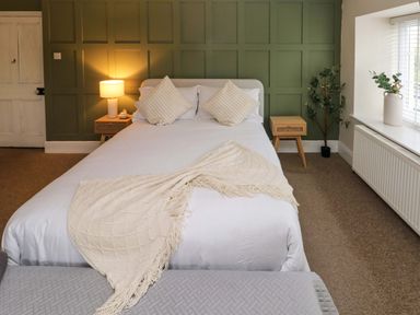 A bedroom with a double bed two bedside tables a lamp plants and a window at Norchard Farm House Redberth near St Florence