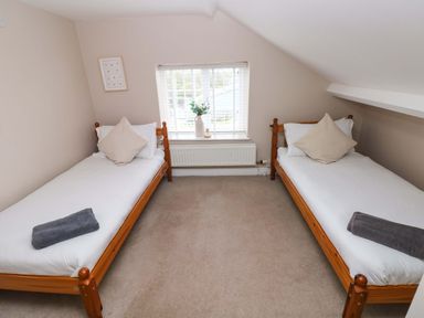 A bedroom with two single beds and a window in the center at Norchard Farm House in Redberth near St Florence